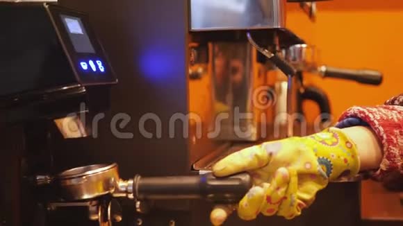 男人或女人咖啡师双手戴着黄色手套用现代咖啡机在现代咖啡机里磨咖啡豆视频的预览图