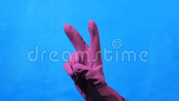 穿紫色橡胶手套的清洁手代表蓝色背景的胜利视频的预览图