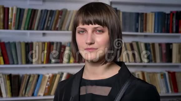 一位留着短发的年轻美女站在图书馆看着摄像机视频的预览图