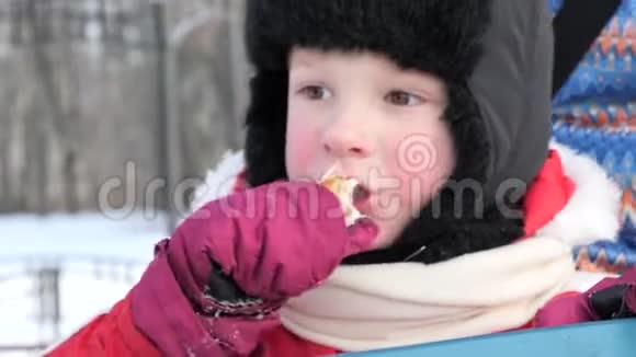 一个小孩子正在冬天的寒冷中吃饭视频的预览图