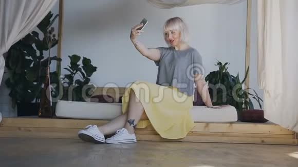 总计划一个留着白发的女孩坐在一张漂亮的床的边缘拿起电话凯菲女人在一个视频的预览图