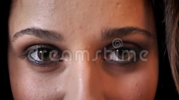 黝黑头发的美女的眼睛在微笑在镜头前看着砖背景视频的预览图