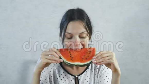 布鲁内特女人在白色背景下吃多汁的西瓜视频的预览图