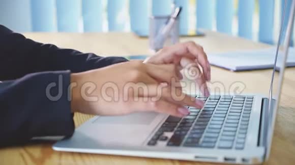 在办公室背景下的笔记本电脑上工作的人手办公室里的一位年轻妇女在键盘上拨文件视频的预览图
