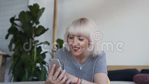 女孩在手机上看照片时微笑一个女人躺在床上背景是白色的墙壁和一个大的视频的预览图