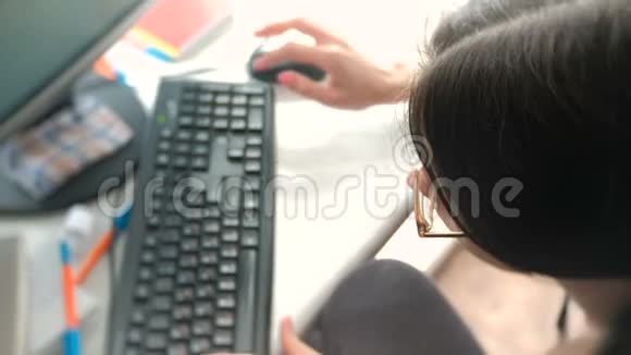 戴眼镜的黑发女人正在电脑键盘上打字视频的预览图