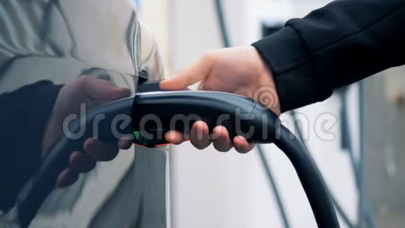 加油喷嘴是从电动汽车的填料孔中抽出的视频的预览图