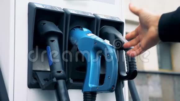 男性手抽出一个电动加油喷嘴来给电动车充电视频的预览图