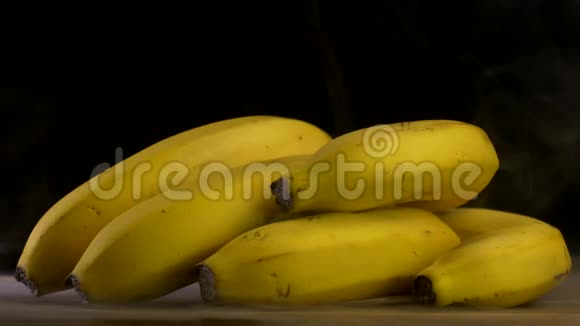 一堆黑色背景的新鲜香蕉来自汗水和凉爽烟雾特写4K视频的预览图