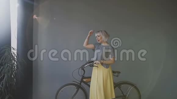一个金发女人的肖像她长着雀斑站在灰色的墙壁上驾驶着她的自行车一个女孩视频的预览图
