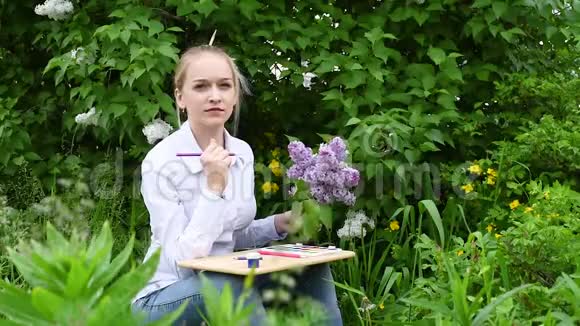 女孩花园里紫丁香背景下的艺术家视频的预览图