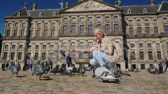 一个年轻的女人正在水坝广场阿姆斯特丹中心喂鸽子欧洲和荷兰的旅游业概念视频的预览图