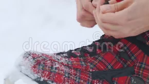冬季一个女人坐下来开始把鞋带系在鲜红的溜冰鞋上视频的预览图