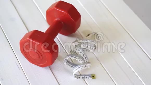 白色木桌上的红色健身哑铃和厘米胶带视频的预览图