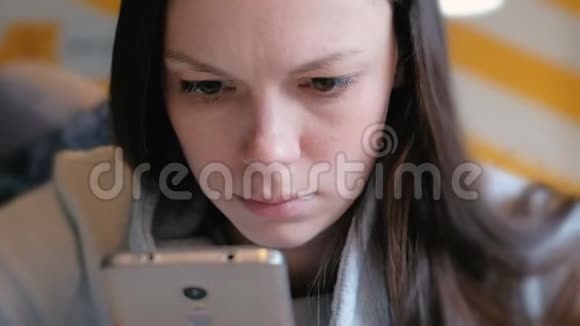 年轻严肃的女人坐在咖啡馆里用手机读东西特写的脸视频的预览图