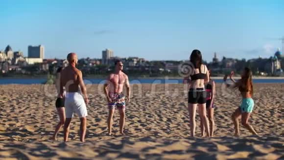 运动的年轻人在河边的沙滩上打排球视频的预览图