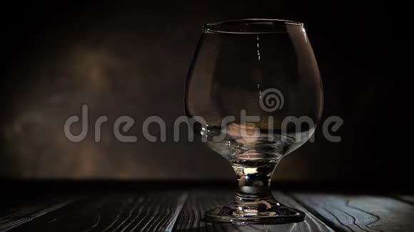白兰地被倒进玻璃杯里在黑暗的背景下视频的预览图