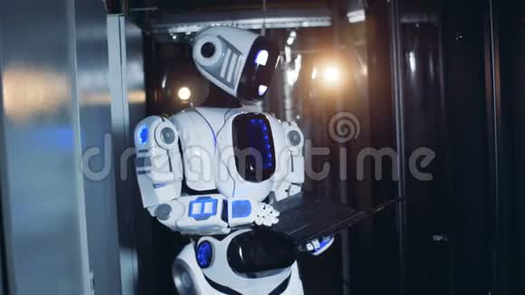 一个机器人在数据中心工作机器人站在服务器机房里手里拿着一台笔记本电脑视频的预览图