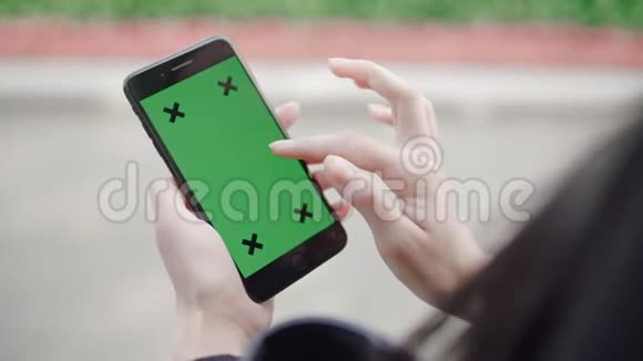 女性手握触摸屏设备使用带有绿色屏幕色度键的智能手机视频的预览图
