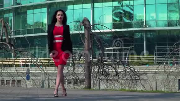 在商务中心附近一位穿着红色连衣裙跳舞的漂亮女商人视频的预览图