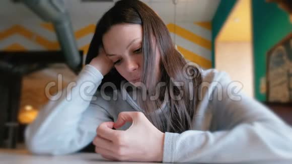 悲伤的女人坐在咖啡馆里等待她的命令看着她的手指特写镜头视频的预览图