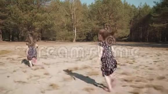 两个女孩在夏天的森林里奔跑在沙滩上视频的预览图