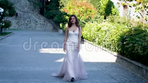 美丽的新娘穿着白色连衣裙沿着大街散步视频的预览图