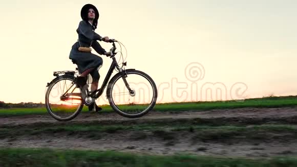 小女孩戴着帽子骑着自行车在草原上视频的预览图