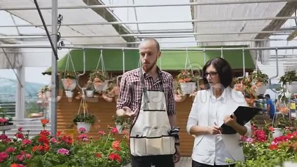 年轻人是农业部门的工人去温室和检查观赏植物园丁男人和女孩视频的预览图