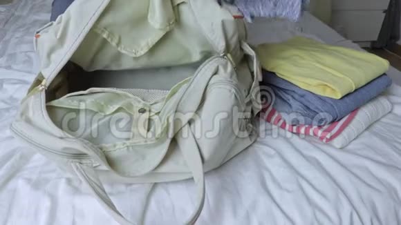 女人坐在床上打开一个袋子从一个行李袋里拿出衣服视频的预览图