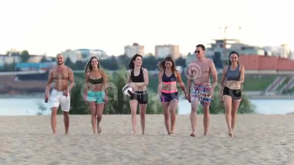 年轻漂亮的运动男女在沙滩上打完排球后谈笑风生视频的预览图