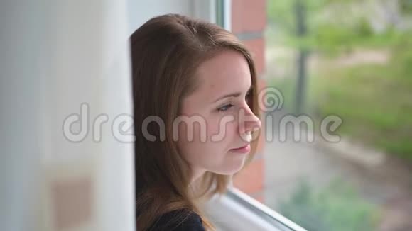 年轻女子望着窗外在家等人视频的预览图