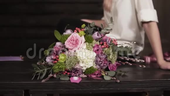 漂亮的慢镜头一个令人惊叹的花束由专业花商穿着白色衬衫的迷人微笑的女孩视频的预览图