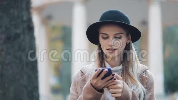 商务女士戴着黑色帽子在户外用手机发送音频语音信息与移动助理交谈女孩使用视频的预览图