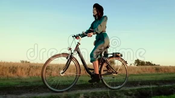 小女孩戴着帽子骑着自行车在草原上视频的预览图
