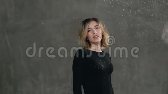一个可爱的女孩站在工作室的灰色墙壁的背景上那里有白色的粉末或面粉视频的预览图