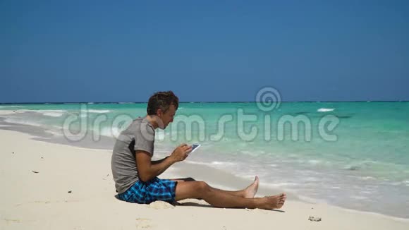 在海滩上拿着平板电脑的人视频的预览图