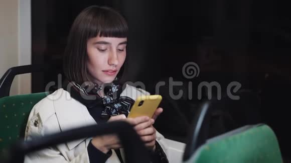 有魅力的年轻女性在公共交通中使用手机她在发短信检查邮件聊天或新闻视频的预览图