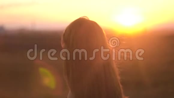 美丽的长发女人的肖像背景是夕阳的阳光头发飘动的迷人女子视频的预览图