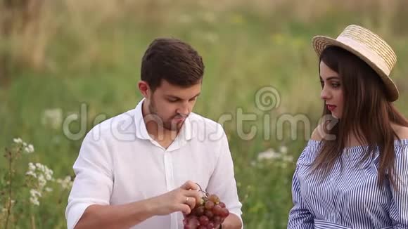 漂亮的夫妇男人和孕妇吃红葡萄健康食品新鲜水果快乐的女人微笑视频的预览图