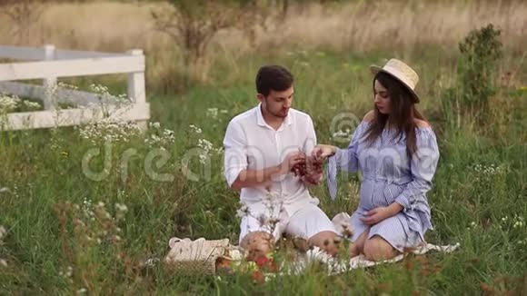 漂亮的夫妇男人和孕妇吃红葡萄健康食品新鲜水果快乐的女人微笑视频的预览图