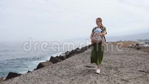 夏天宝宝和妈妈在海上幸福的家庭在户外散步儿童在一个载体背包妇女与妇女视频的预览图