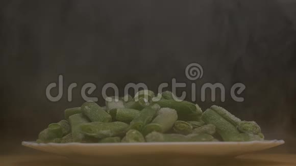 新鲜冷冻芦笋豆荚在黑色的背景下吹出凉爽和新鲜烟雾特写慢动作视频的预览图