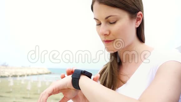 一个人在海滩上用智能手表的女人女性通过慢动作智能手表与朋友聊天视频的预览图