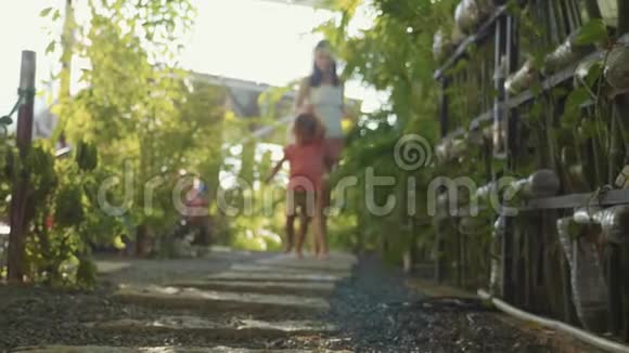 妈妈和小女孩在花园的小路上散步双脚靠近镜头视频的预览图