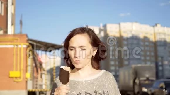 一个深色的女人正在吃冰淇淋上面有巧克力糖霜女孩去吃巧克力冰淇淋视频的预览图