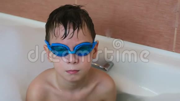 男孩67岁坐在泡泡浴里用眼镜游泳看着相机微笑着视频的预览图