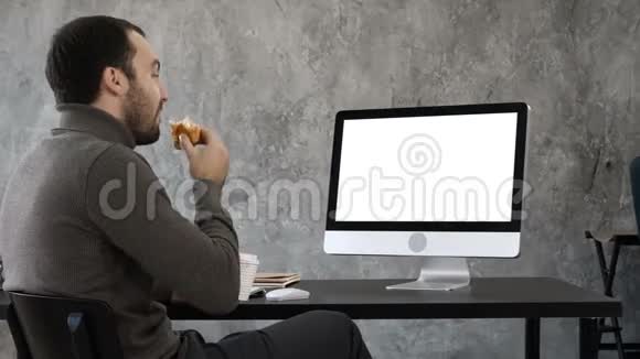 英俊的商人吃东西和某人开视频会议白色显示器视频的预览图