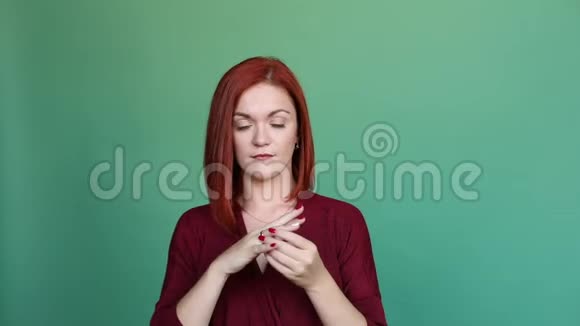 红头发的女人在绿色背景的工作室摆姿势从手指上掏出戒指视频的预览图