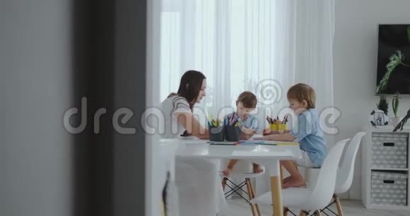 妈妈帮儿子学画做作业学前准备在家坐在白色厨房两个孩子视频的预览图